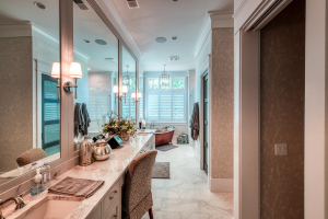 A master bathroom with marble flooring, a copper soaking tub at the far end, and a gray double vanity with a bank of mirrors at the near end.