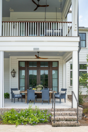 Motorized retractable screens, mahogany doors, haint blue v-groove ceilings, Bevolo gas lanterns. Large white house with double back porches, bench swing, outdoor dining table, rich brown mahogany doors, and haint blue v-groove ceilings.