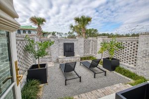 A small, brick-enclosed courtyard with a water feature, lush landscaping, and a water feature on one wall.