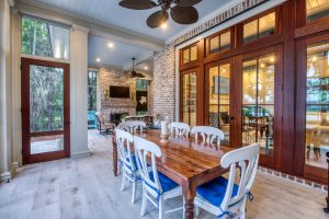 Brick fireplace, porcelain tile floors, and mahogany doors. A screened porch with a brick fireplace and outdoor dining area.