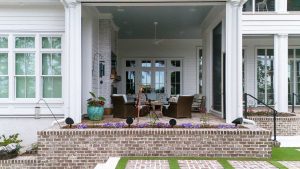 Brick patio, fireplace with seating area, and motorized porch screens. Outdoor living area with brick patio, fireplace, and seating in a Palmetto Bluff home built by CS Thomas Construction.