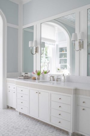 Primary bathroom in a Palmetto Bluff home built by CS Thomas Construction with arched mirrors, white cabinetry, and hex tile floor.
