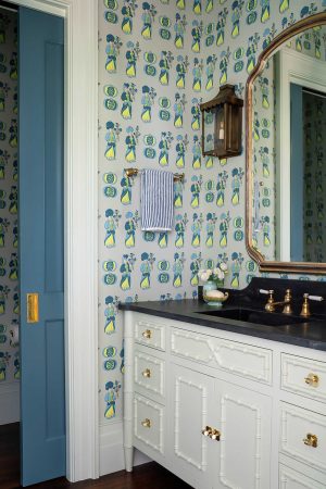 Guest bathroom in a Palmetto Bluff home built by CS Thomas Construction with patterned wallpaper and brass fixtures.