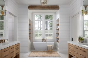 Bright bathroom with freestanding tub, wood vanities, and shiplap walls by CS Thomas Construction.