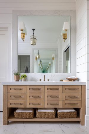 Vanity with light oak cabinetry, marble countertop, and brass fixtures.