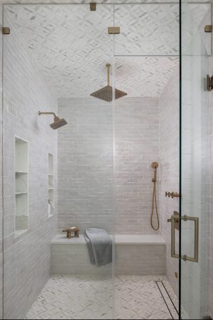 Marble-tiled walk-in shower with dual rainheads and brass fixtures.