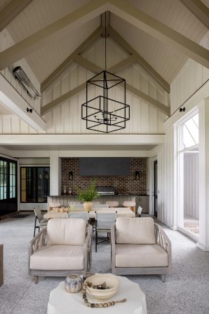 Details: vaulted ceiling, scissor trusses, motorized screen, porch heaters, built-in grill, brick backplash. Vaulted outdoor dining area with brick grill wall and modern lighting.