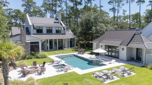 Backyard with modern pool, sun loungers, and fire pit at a Palmetto Bluff home.