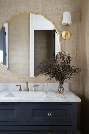 Elegant powder room with marble vanity, brass fixtures, and textured wallcovering.
