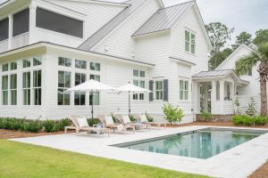 Modern backyard with pool, white exterior siding, and lounge chairs in Palmetto Bluff, Bluffton SC.