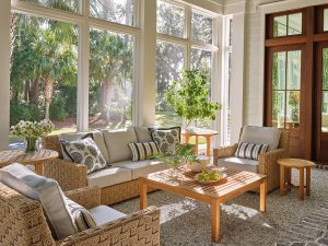 Details: tabby concrete, brick hearth, mahogany doors. Inviting screened porch with woven lounge furniture, natural light, and views of palms and oaks in Palmetto Bluff.