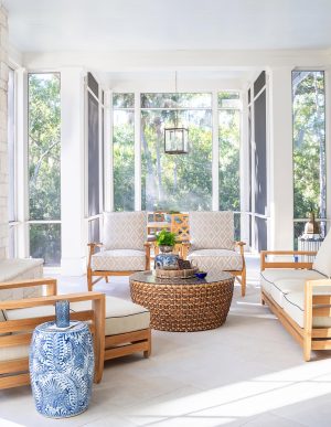 Details: stone fireplace surround, tile floors, spacious sitting area. Screened porch with natural wood furniture, woven coffee table, and views of lush Lowcountry trees.